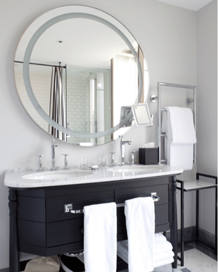 Gray renovated bathroom/vanity area with two sinks and a large round mirror